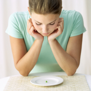 woman looking at a pea on a plate